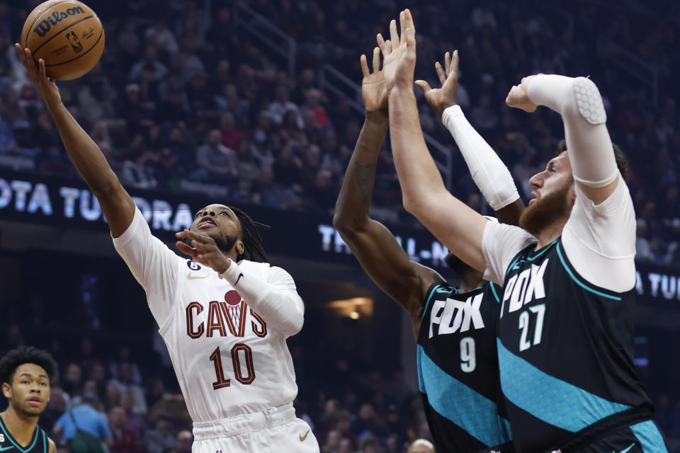 Cleveland Cavaliers guard Darius Garland (10) shoots as Portland Trail Blazers center Jusuf Nurkic (27) and forward Jerami Grant (9) defend during the first half of an NBA basketball game, Wednesday, Nov. 23, 2022, in Cleveland. (AP Photo/Ron Schwane)