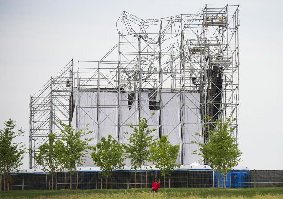 A man stands near a collapsed stage at Downsview Park in Toronto on Saturday, June 16, 2012. Toronto paramedics say one person is dead and another is seriously hurt after the stage collapsed while setting up for a Radiohead concert. They say two other people were injured and are being assessed. (AP Photo/The Canadian Press, Nathan Denette)