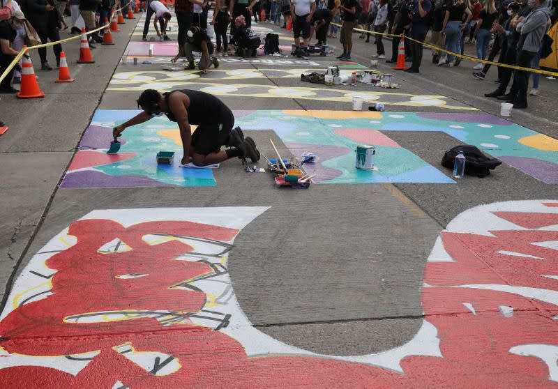 Protesters decorate a freshly painted sign that reads 'Black Lives Matter' during a protest against racial inequality and call for defunding of Seattle police, in Seattle