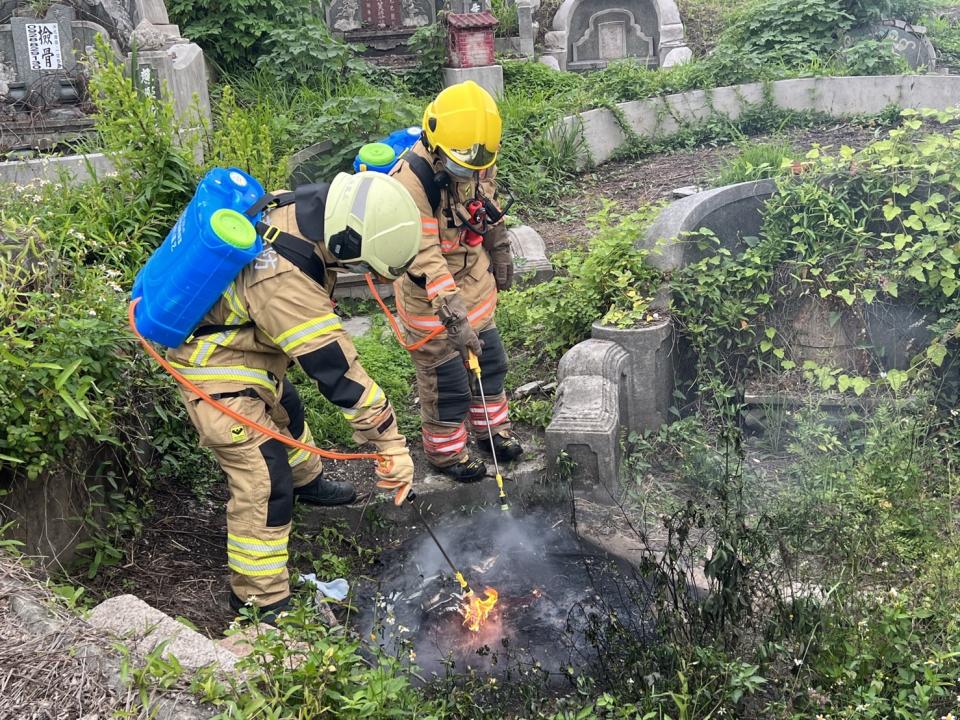 民眾掃墓不慎引火，消防人員以背負式滅火桶到場滅火，防止擴大延燒。（消防局提供）