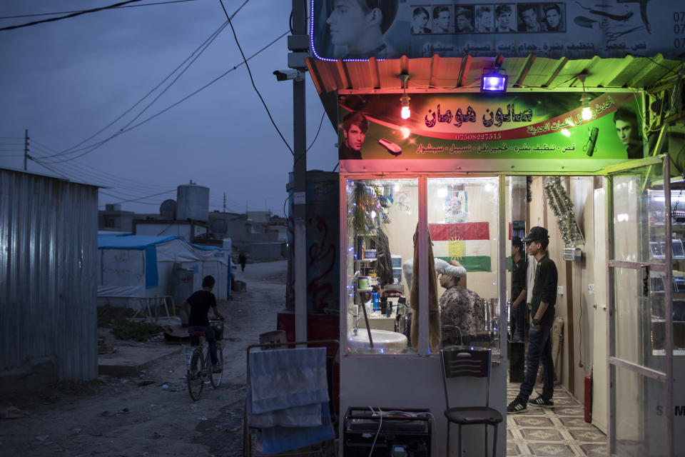 Syrians stand in a barber shop in the Kawergosk refugee camp in northern Iraq, Saturday, April 8, 2017. For the millions of Syrian refugees scattered across camps and illegal settlements across the region, the chemical attack on a town in northern Syria and subsequent U.S. strike was a rare moment when the world briefly turned its attention to Syria, before turning away again. (AP Photo/Felipe Dana)