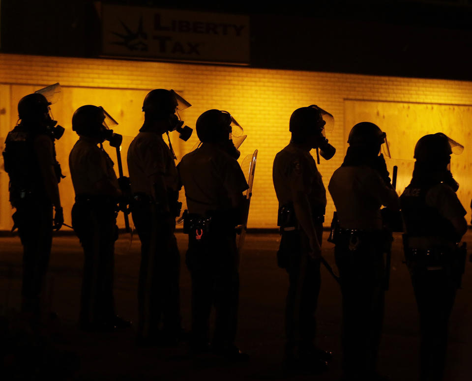 FILE - Police wait to advance after tear gas was used to disperse a crowd during protests against the shooting death of Michael Brown Jr. on Aug. 17, 2014 in Ferguson, Mo. (AP Photo/Charlie Riedel, File)