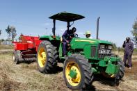 David Kayi, a Hello Tractor engineer, installs an application on a John Deere 5503 tractor, using the Hello Tractor technology that connects farmers with vehicles' owners, at a hay farm in Umande village in Nanyuki
