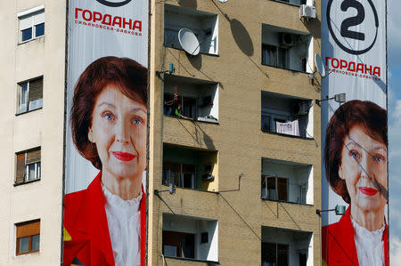 A woman cleans her balcony next to an election campaign poster of the opposition presidential candidate Gordana Dafkova-Siljanovska for presidential election on April 21 in Skopje, North Macedonia April 19, 2019. REUTERS/Ognen Teofilovski