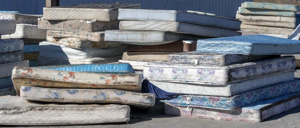 Dirty used mattresses piled at recycling site.