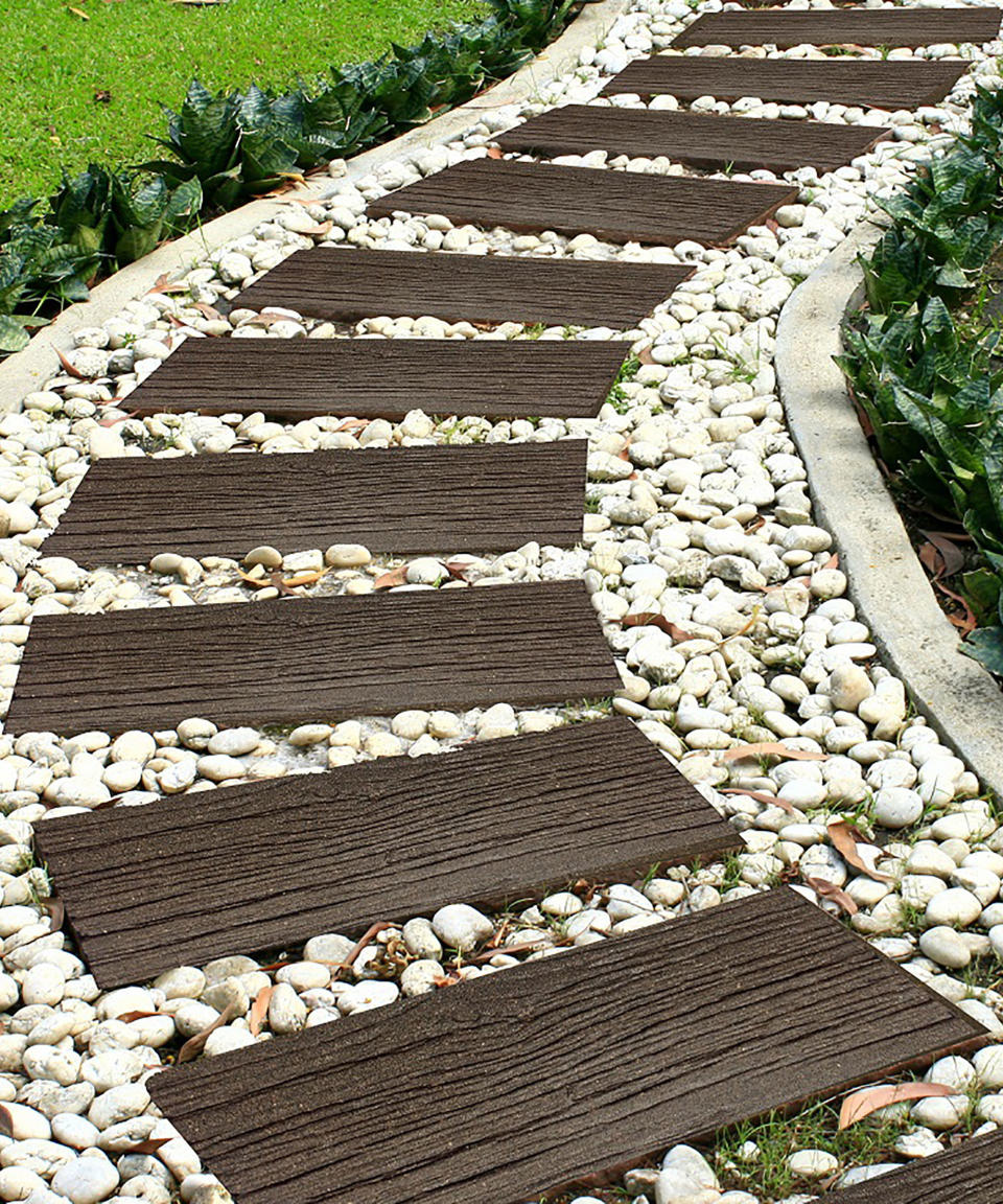 <p> You can use sleepers or railroad ties – either short timber sleeper lengths or outdoor porcelain tiles designed to look like wood – in the same informal way as circular stepping stones. Just lay them horizontally into turf for a cheap DIY garden path.  </p> <p> However, it’s also possible to create a more formal path with sleepers by surrounding them with gravel, chippings or pebbles and encasing the path with a hard border, such as a concrete edging.  </p> <p> The material surrounding a sleeper path can be in either a complementary or contrasting color. Whatever your choice, landscaping with timbers in this way provides a strong design feature in a garden and it doesn't have to cost a fortune. It's a good way to lead into a hidden corner of garden; the horizonal placing of each sleeper acts like a ladder leading forward. </p>