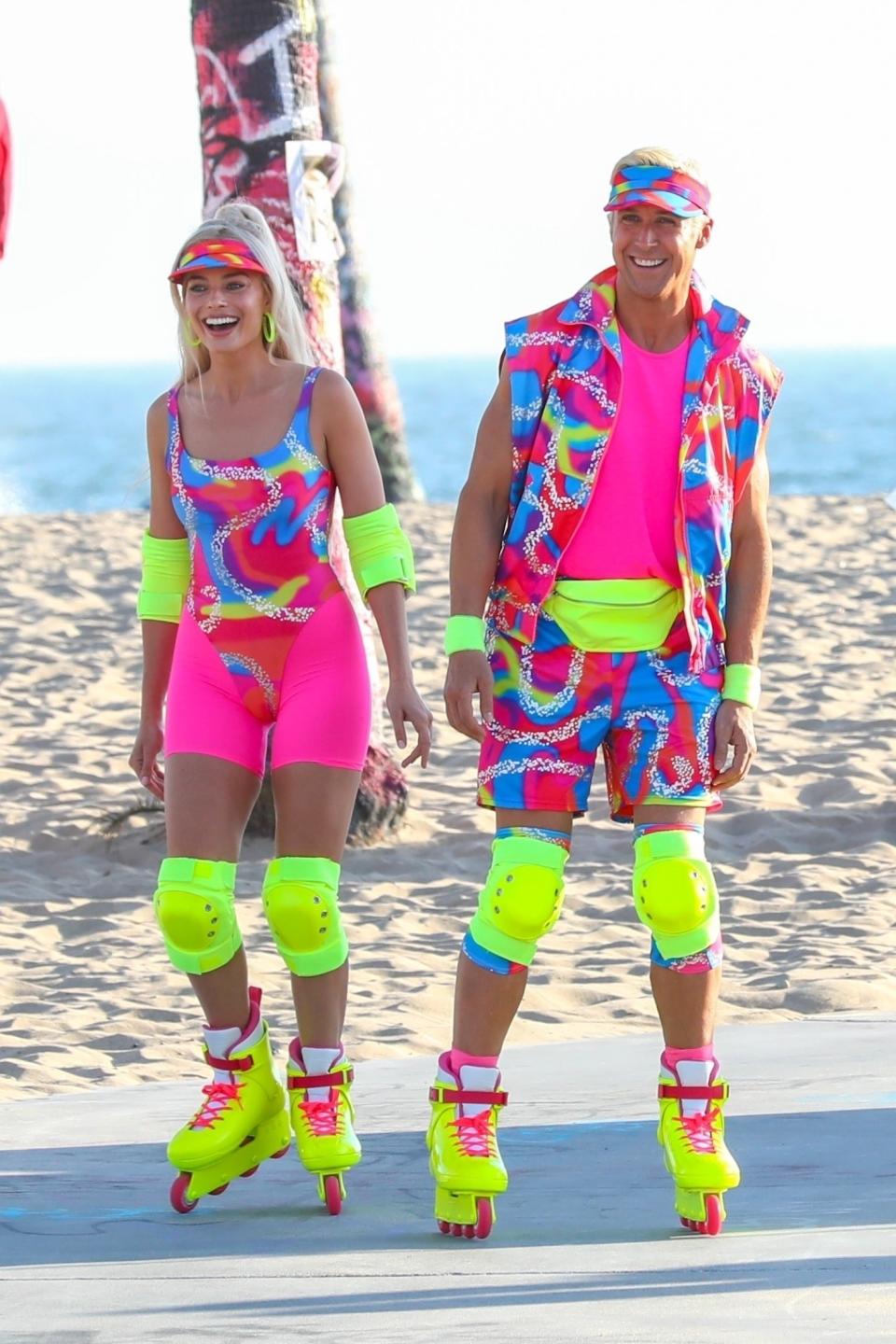 Ryan and Margot wearing matching outfits with bright colors that look like they're from the '80s, as well as matching knee pads and rollerblades