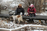 Sasha, de 49 años, y Lyusya Stepanova, de 44, se sientan junto a su perro sobre una tubería caliente en Omsk (Rusia). Son dos de las personas sin hogar que hay en esta ciudad situada en pleno centro de Siberia. (Foto: Alexey Malgavko / Reuters).