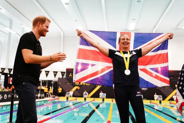 Harry congratulates a Team UK medal winner holding a Union flag after the swimming at the Invictus Games at the Hague