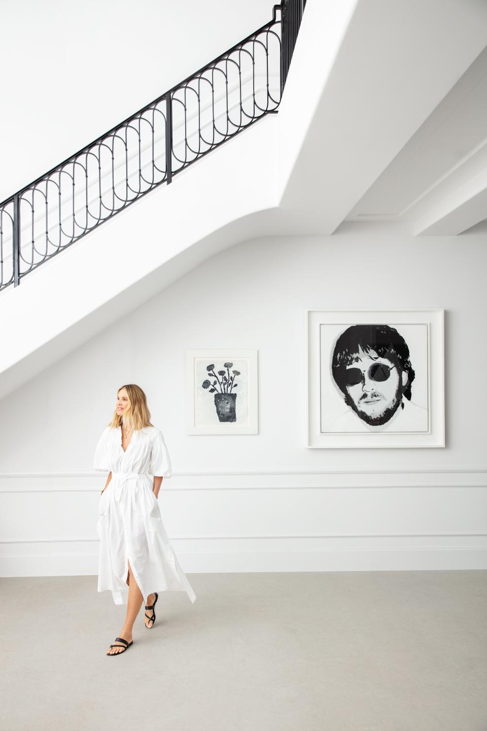 Elle Macpherson wears a Chloé dress and Manolo Blahnik sandals in the foyer of her Florida home. Artworks by Donald Baechler (left) and Andy Warhol. Architecture throughout by Chad Oppenheim.