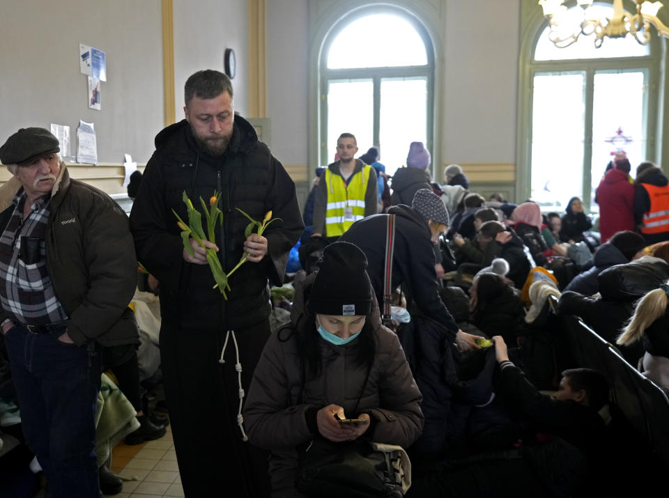 A Catholic priest hands out tulips, to women who have fled Ukraine, in recognition of International Women's Day at the train station in Przemysl, Poland, Tuesday, March 8, 2022. U.N. officials said Tuesday that the Russian onslaught has forced 2 million people to flee Ukraine. It has trapped others inside besieged cities that are running low on food, water and medicine amid the biggest ground war in Europe since World War II. (AP Photo/Czarek Sokolowski)