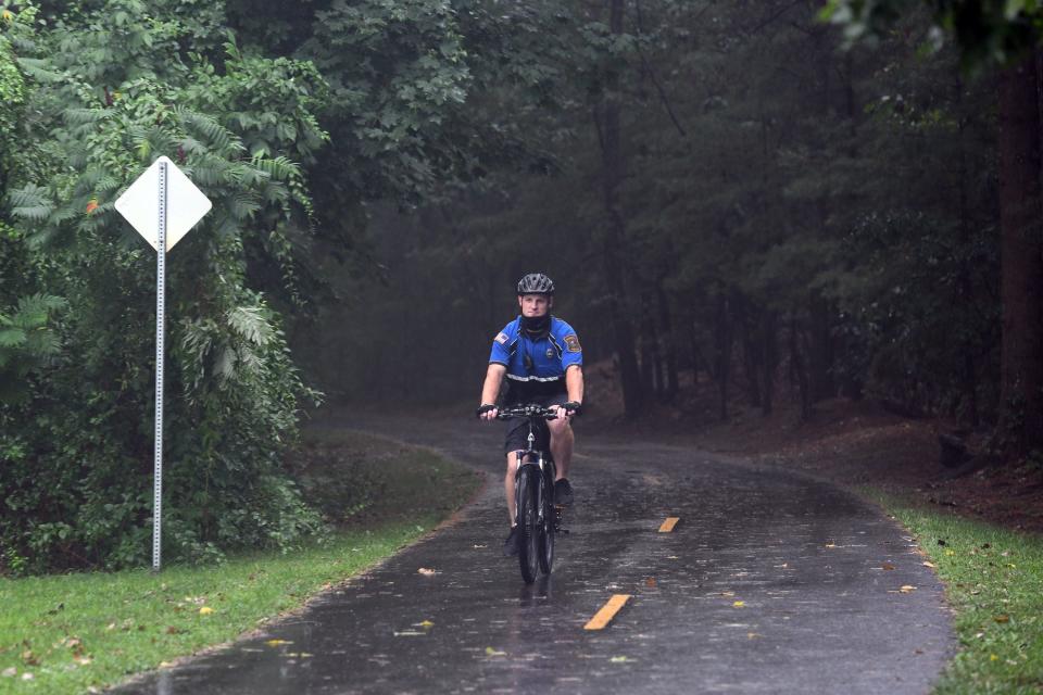 Hudson Police Det. Shamus Veo rides along the Assabet River Rail Trail in Hudson, Aug. 29, 2020.