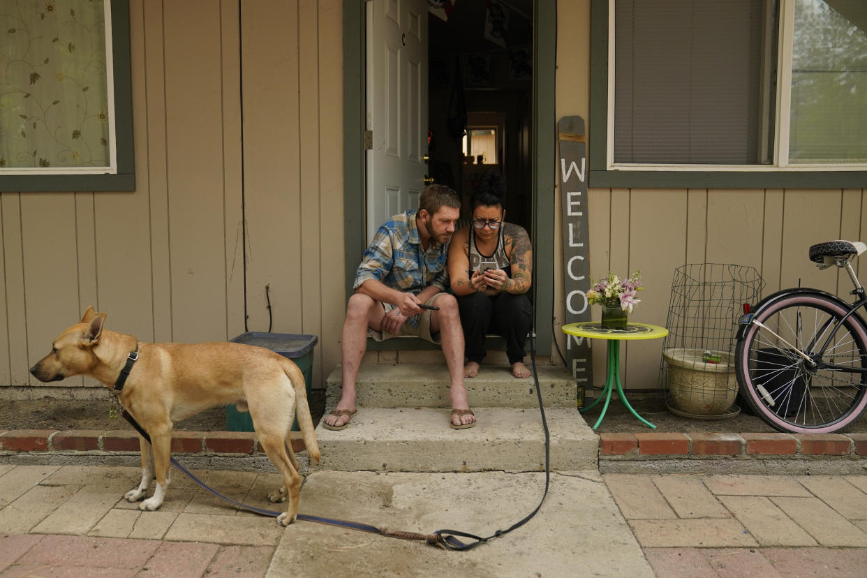 Sierra Fowzer, right, and Skylor Klitsch, a couple who chose not to evacuate, look at their phone for updates on the Caldor Fire in South Lake Tahoe, Calif., Tuesday, Aug. 31, 2021. "This is our home. That is a special reason. This is where we live," said Fowzer. (AP Photo/Jae C. Hong)