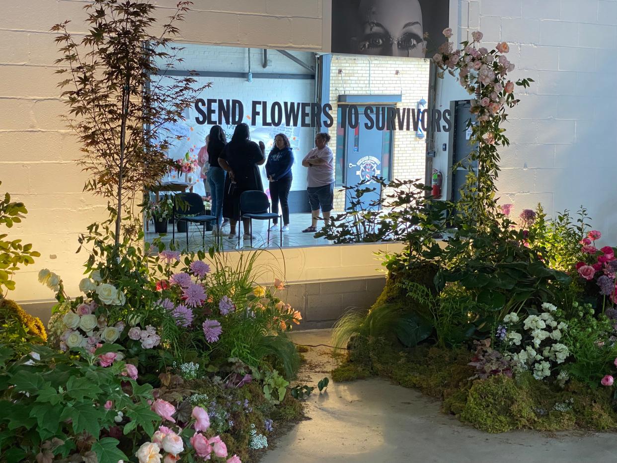Guests and artists are reflected in the mirror feature of the Send Flowers to Survivors installation by The Wild Mother Creative Studio.