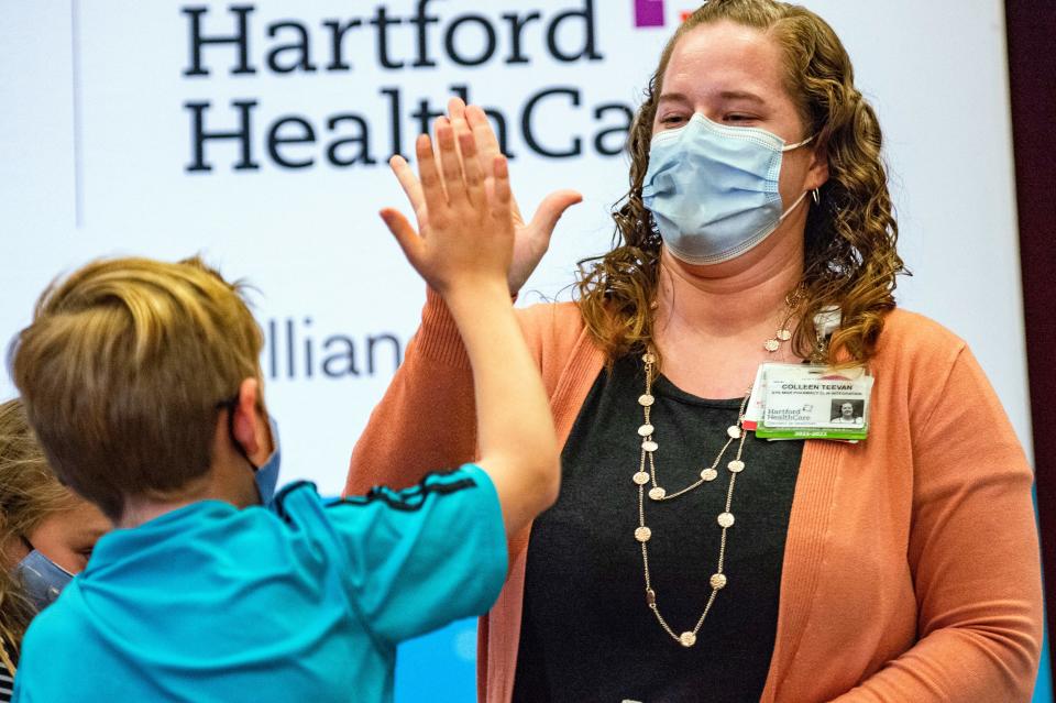 A ten year old boy high fives a pharmacist after receiving the Covid-19 vaccine at Hartford Hospital in Hartford, Connecticut.