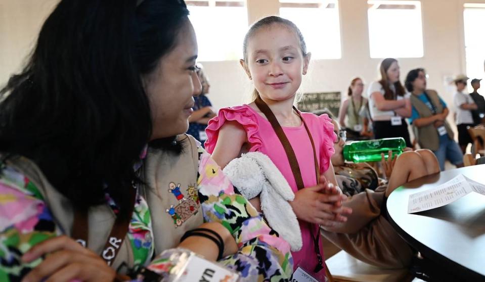 Samantha Urias Ponce, de 7 años, a la derecha, y la consejera Katelyn Sampang asisten a la orientación al inicio del campamento en Camp Taylor, en Grayson, California, el martes 11 de junio de 2024.
