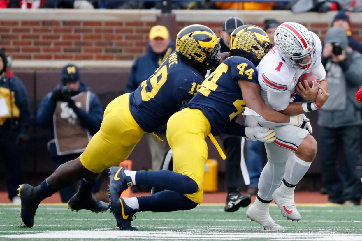 Ohio State quarterback Justin Fields is tackled by Michigan Wolverines linebacker Cameron McGrone (44) and defensive lineman Kwity Paye (19) in the first half at Michigan Stadium, Nov. 30, 2019 in Ann Arbor.