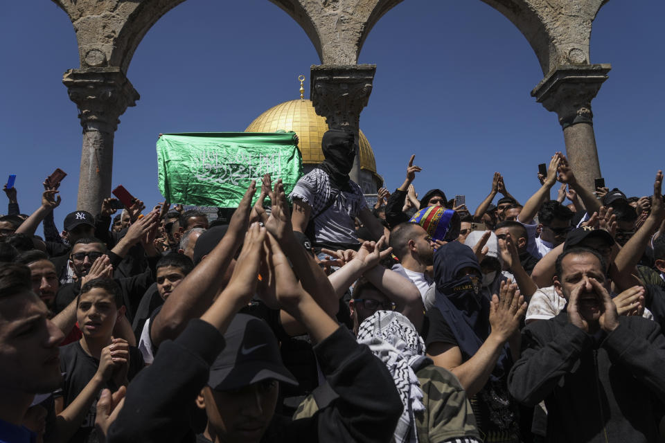 Palestinians chant slogans and wave Hamas flags during a protest against Israel, in front of the Dome of the Rock shrine at the Al Aqsa Mosque compound in Jerusalem's Old City, Friday, April 15, 2022. Palestinians clashed with Israeli police at the Al-Aqsa mosque compound in Jerusalem before dawn on Friday as thousands gathered for prayers during the holy month of Ramadan. Medics said that more than 150 Palestinians were wounded. (AP Photo/Mahmoud Illean)