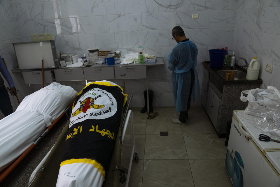 A morgue worker prepares the bodies of Mohammed Ghali (right) and Mahmoud Abdeljawwad (left), who were killed alongside Islamic Jihad commander Ali Ghali (unseen) killed in an Israeli airstrike, prior to their funeral in Khan Younis, southern Gaza Strip, Thursday, May 11, 2023. (AP Photo/Fatima Shbair)