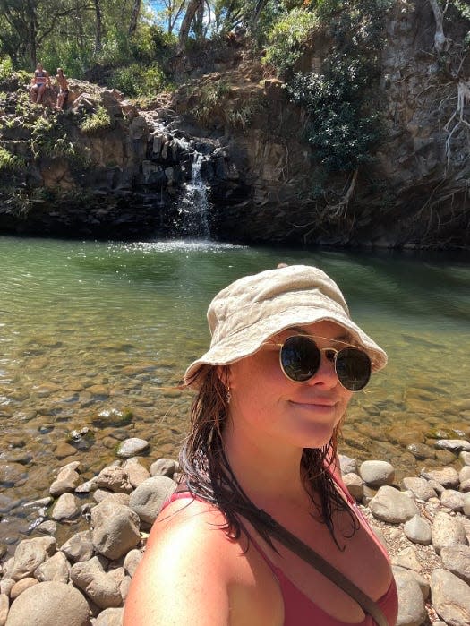 Teaghan Skulszki standing in front of hawaii waterfall maui