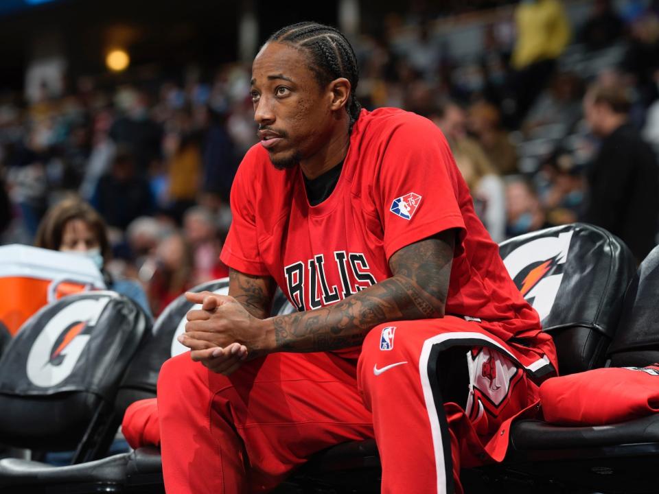 DeMar DeRozan sits on the bench in the Bulls' warmup clothes.