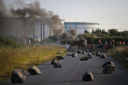 French union workers and protestors stand near a burning barricade to block the entrance of the fuel depot of the SFDM company near the oil refinery of Donges, France, May 25, 2016 over proposed new labour laws. REUTERS/Stephane Mahe