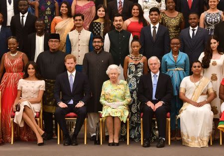 Britain's Queen Elizabeth, Prince Harry and Meghan, the Duchess of Sussex pose for a picture with some of Queen's Young Leaders at a Buckingham Palace reception following the final Queen's Young Leaders Awards Ceremony, in London, Britain June 26, 2018. John Stillwell/Pool via Reuters