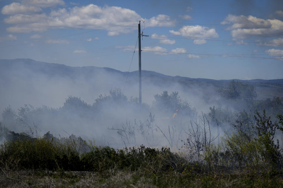 A firefighter directs water on a grass fire on an acreage behind a residential property in Kamloops, British Columbia, Monday, June 5, 2023. No structures were damaged but firefighters had to deal with extremely windy conditions while putting out the blaze. (Darryl Dyck/The Canadian Press via AP)