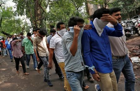 Police escort men who they said were arrested on Wednesday on suspicion of tricking American citizens into sending them money by posing as U.S. tax officials, at a court in Thane, on the outskirts of Mumbai, India, October 6, 2016. REUTERS/Danish Siddiqui