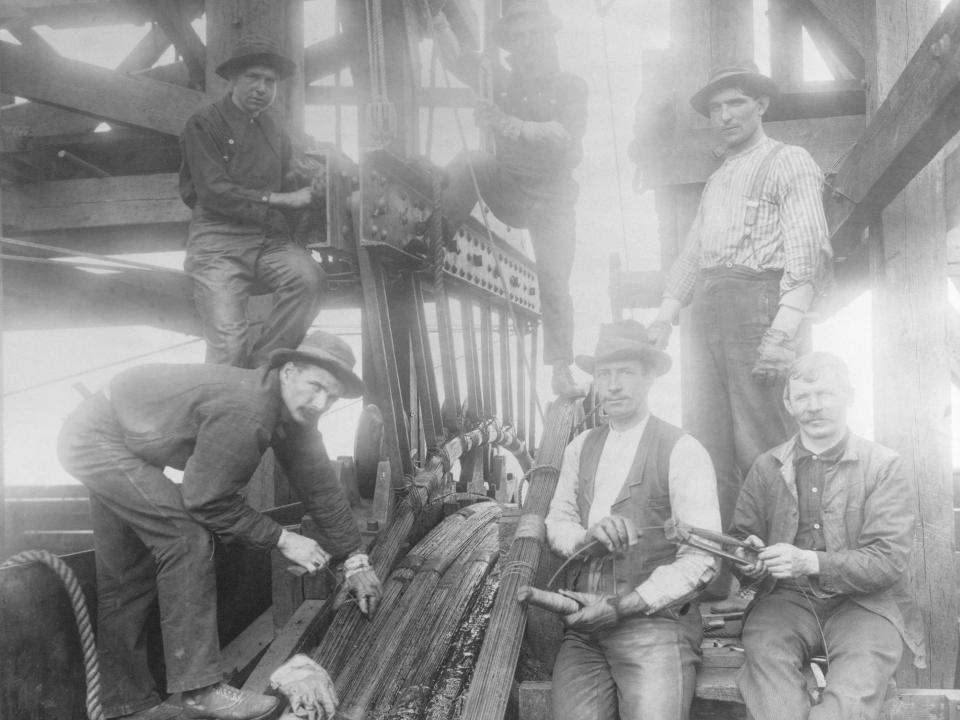 Workmen cutting and tying tension cables