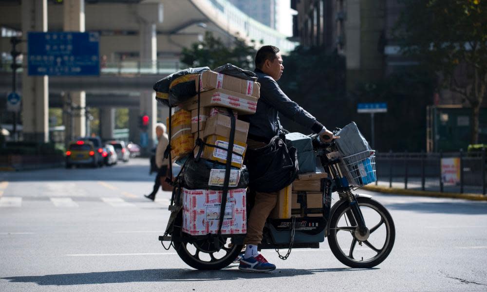 A delivery man on an electric bike crosses a street as he delivers parcels in Shanghai.