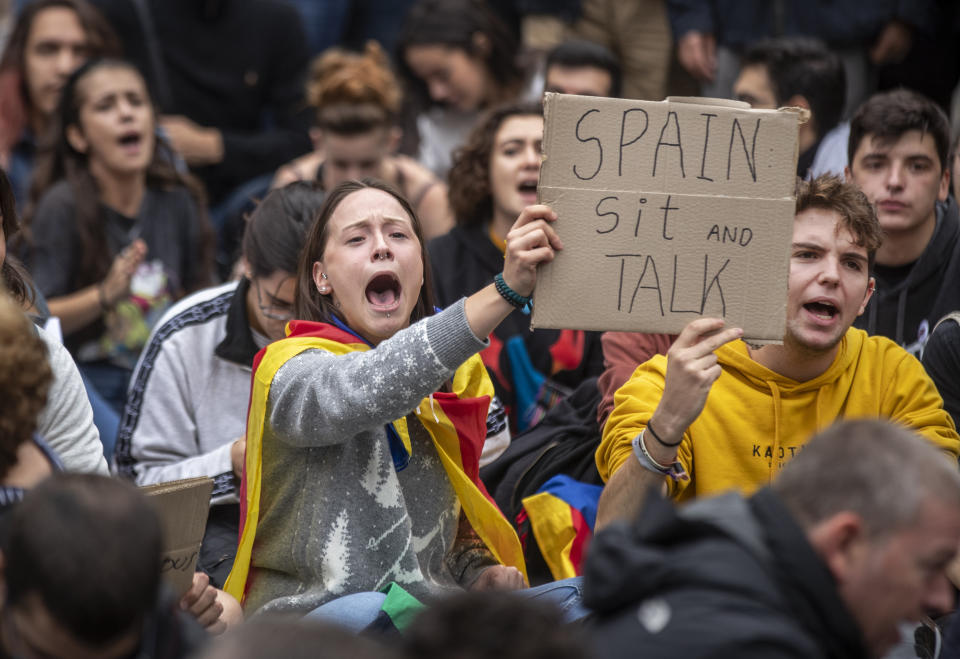 Catalan pro-independence protesters demonstrate outside the building of the Government Delegation in the Autonomous Community of Catalonia, in downtown Barcelona, Spain Monday, Oct. 21, 2019. Spanish leader Pedro Sanchez is traveling to Barcelona Monday, the protest-struck capital of the northeastern Catalonia region, to visit with injured police officers and talks with officials in charge of security. (AP Photo/Ben Curtis)