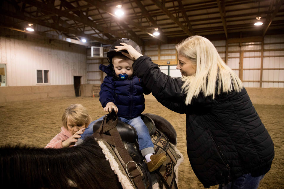 Calum con sus padres, Matt y Tammy Cunningham, y Louann Gross, quien dirige una granja y guardería a la que asiste el niño en Kokomo, Indiana, el viernes 10 de marzo de 2023. (Kaiti Sullivan para el New York Times)