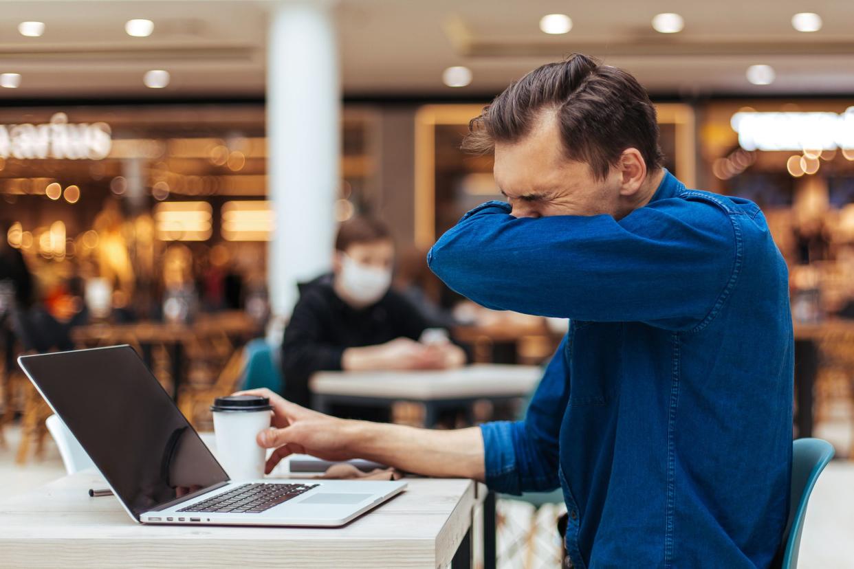 close up . man sneezes sitting at a table in a cafe