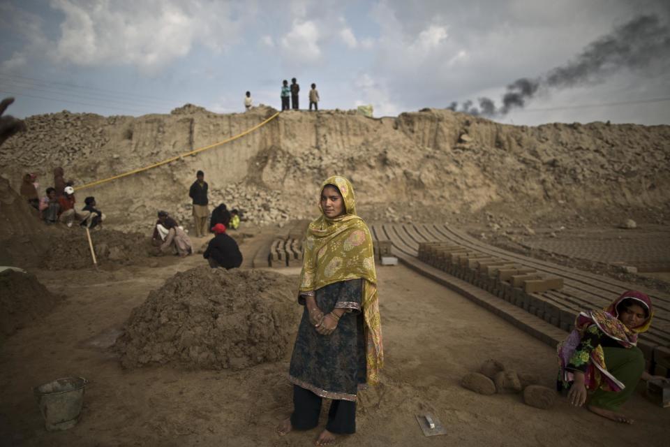 In this Wednesday, March 5, 2014, photo, Navila Shirali, 17, a Pakistani brick factory worker, poses for a picture at the site of her work in Mandra, near Rawalpindi, Pakistan. Navila's father is in debt to his employer the amount of 500,000 rupees (approximately $5000). (AP Photo/Muhammed Muheisen)