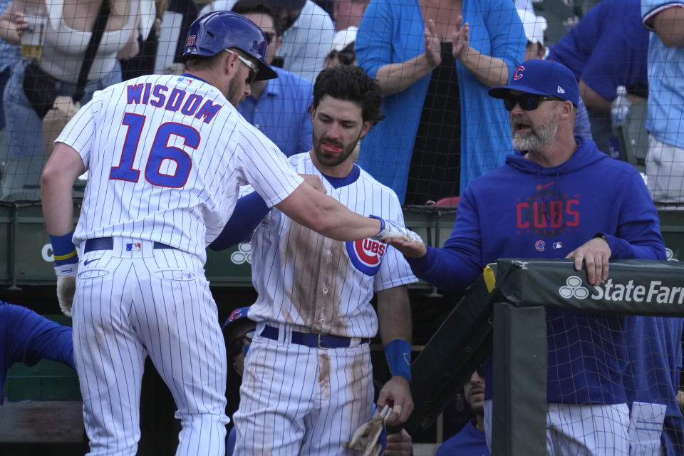 Chicago Cubs' Patrick Wisdom, left, is congratulated by Chicago Cubs manager David Ross, right, and Dansby Swanson after hitting a two-run home run during the eighth inning of a baseball game against the Cincinnati Reds in Chicago, Sunday, May 28, 2023. (AP Photo/Nam Y. Huh)