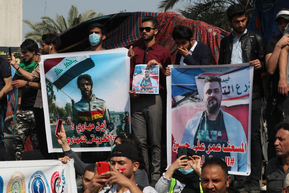 Iraqis hold photos of missing protesters during anti-government protest in Baghdad, Iraq, Sunday, Feb. 23, 2020. There are 25 activists still missing since the protests erupted on Oct. 1, 2019, according to the semi-official Iraqi High Commission for Human Rights. No group has claimed responsibility but activists have blamed the militias. (AP Photo/Khalid Mohammed)