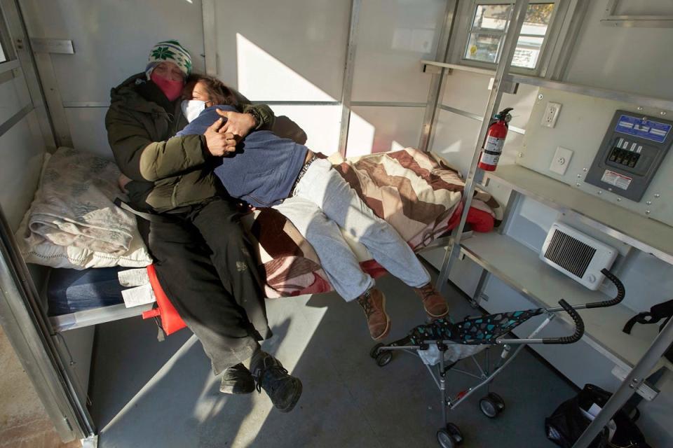 Chris Foss, left, and Tiecha Vannoy embrace after moving into a new pod set up by the city in the Old Town district in Portland, Ore., on Dec. 8, 2020. The pandemic has caught homeless service providers in a crosscurrent: Demand is high, but their ability to provide services is constricted.