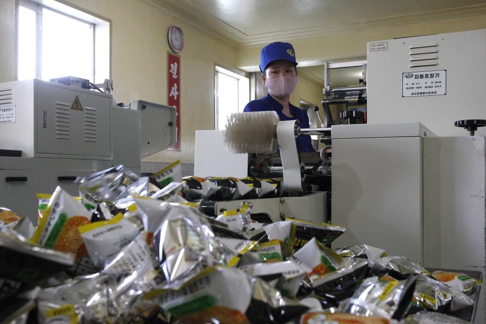 FILE - In this Oct., 28, 2020, file photo, an employee wearing a face mask work on a production line at the Songdowon General Foodstuff Factory in Wonsan, Kangwon Province, North Korea. North Korea is staging an “80-day battle,” a propaganda-heavy productivity campaign meant to bolster its internal unity and report greater production in various industry sectors ahead of a ruling party congress in January. (AP Photo/Jon Chol Jin, File)