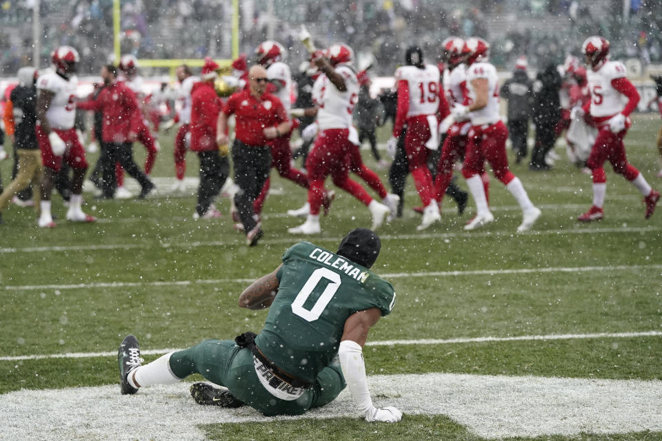 Michigan State wide receiver Keon Coleman sits in the end zone as Indiana celebrates the win after the second overtime of an NCAA college football game, Saturday, Nov. 19, 2022, in East Lansing, Mich. (AP Photo/Carlos Osorio)