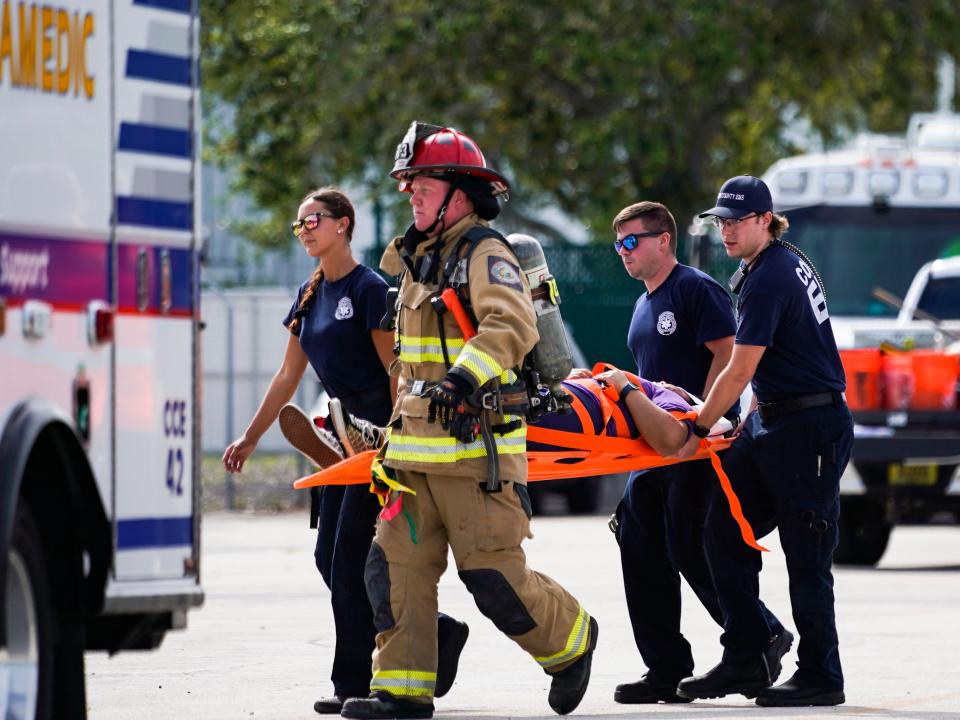 First responders carry students to a triage area during a simulated disaster exercise at Naples Airport on Tuesday, April 25, 2023.