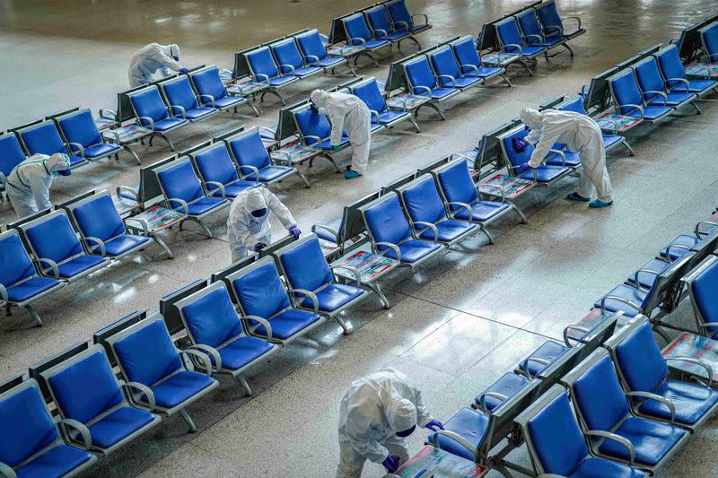 FILE PHOTO: Workers in protective suits disinfect a waiting hall at the Wuhan Railway Station which has been closed due to the novel coronavirus disease (COVID-19) outbreak, in Wuhan