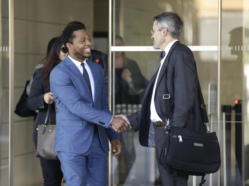 Rapper Marcus Gray, left, shakes hands with his attorney, Michael A. Kahn, right, as they leave the federal courthouse downtown Los Angeles Thursday, Aug. 1, 2019. A jury has decided that Katy Perry, her collaborators and her record label must pay more than $2.78 million because the pop star's 2013 hit "Dark Horse" copied a Christian rap song. It was an underdog victory for relatively obscure artist Gray, whose 5-year-old lawsuit survived constant court challenges. (AP Photo/Damian Dovarganes)