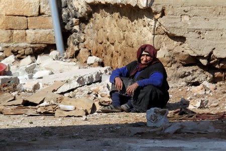 A women rests near rubble on the ground in the town of Darat Izza, province of Aleppo, Syria February 28, 2016. REUTERS/Ammar Abdullah