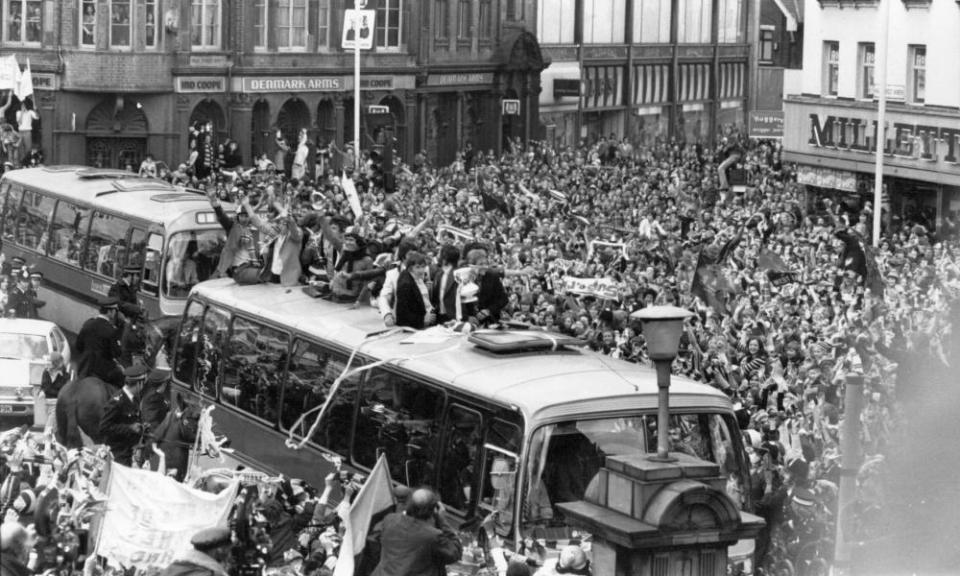 West Ham celebrate their 1975 FA Cup final win from the top of a coach as fans pack the street.