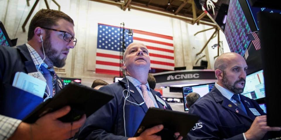 An American flag hangs behind traders working on the floor of the New York Stock Exchange (NYSE) on October 11, 2019 in New York City.