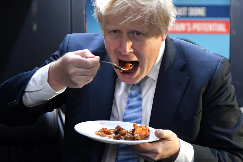 Britain's Prime Minister Boris Johnson eats a portion of pie on the campaign bus after a visit to the Red Olive catering company in Derby, Britain December 11, 2019 on the final day of campaigning before a general election. Ben Stansall/Pool via REUTERS