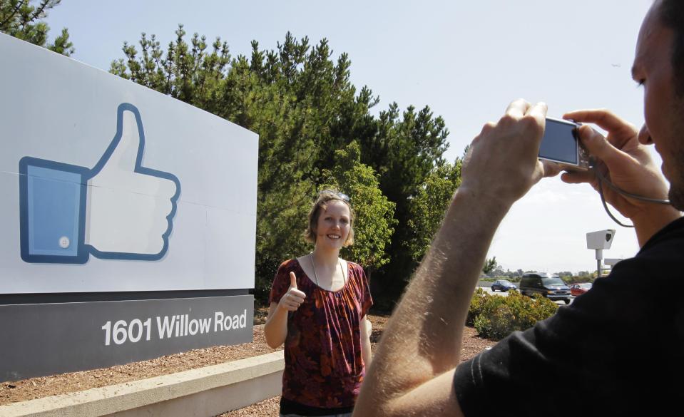 German tourists who use Facebook, take pictures outside of Facebook headquarters in Menlo Park, Calif., Friday, Aug. 17, 2012. Facebook stock is trading at $19 and has lost half its market value since its May public offering. (AP Photo/Paul Sakuma)