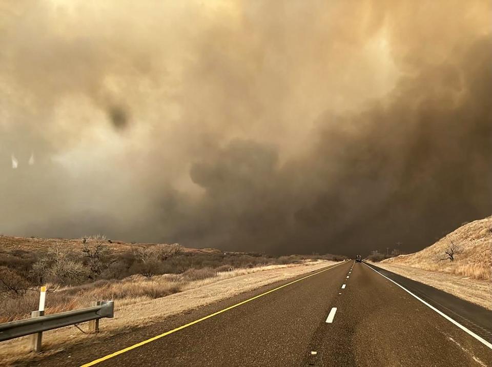In this handout photo provided by the Texas A&M Forest Service, smoke billows over a road Tuesday during the Smokehouse Creek fire in the Texas Panhandle. The fire has grown to cover about 500,000 acres.