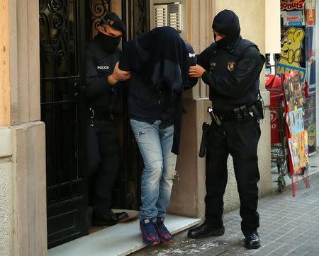 Spanish police lead a suspect from an apartment building during a sweeping operation at some 12 locations against Islamist militants in which eight people were arrested in Barcelona, Spain, April 25, 2017. REUTERS/Albert Gea